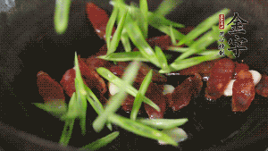 先后下香腸片、四季豆絲均勻翻炒，加適量清水燜煮一下。