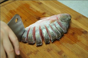 將鱸魚清洗干凈，從脊椎處切斷至腹部，腹部保留1cm左右不要切斷。