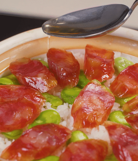 大米出現(xiàn)小孔時開蓋放香腸，往鍋邊淋入少許油，再燜煮8~10分鐘左右。