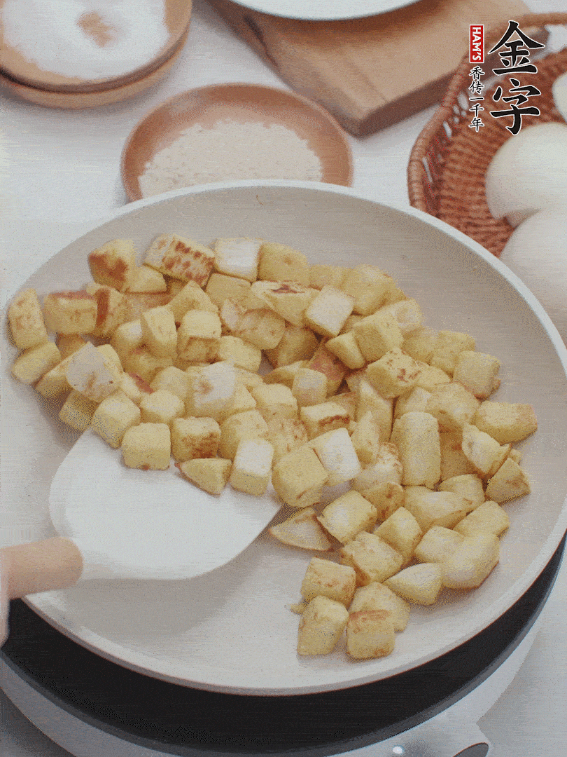 起鍋熱油，倒入饅頭丁，小火煎至蛋液凝固定型再翻面，饅頭丁部煎至金黃時(shí)盛起待用。